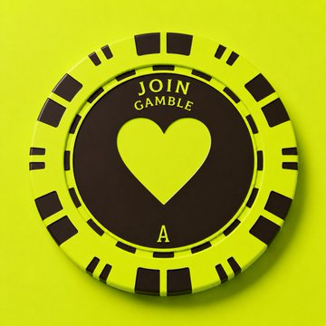 A neon green poker chip with a heart design and the text 'JOIN GAMBLE' on it.