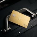 A gold-colored credit card rests on top of a black magnetic stripe card reader, likely at a retail counter.