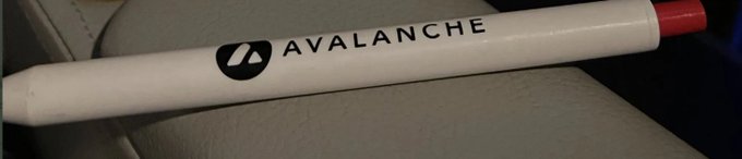 A white promotional pen with a red cap displays the "AVALANCHE" logo and name, resting on what appears to be a beige leather seat. The item matches the lost Avax pen the poster mentioned, which they received from the Avalanche community and are hoping to replace.