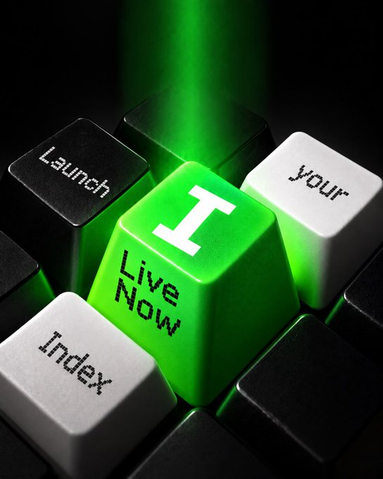 A glowing green computer keycap emblazoned with "I Live Now" and "1" rises above a dark keyboard, surrounded by black and white keys reading "Launch," "your," and "Index," visually echoing the announcement of the $INDICIS token launching on Robinhood and the concept of pairing meme tokens into custom indexes.