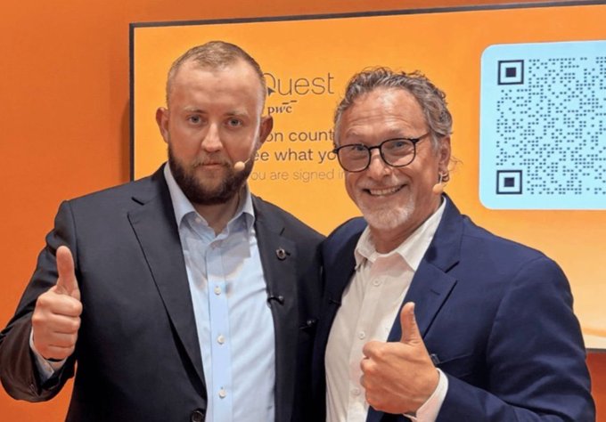 Two men in business suits giving thumbs up at what appears to be a PwC event, with a QR code visible on the orange backdrop.
