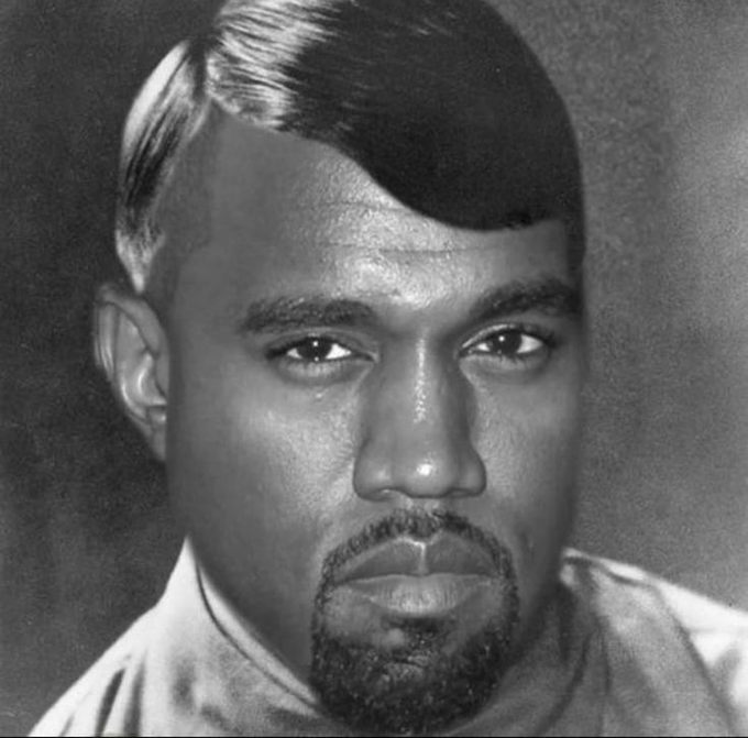 A black and white close-up portrait of a man with short hair and a goatee, looking directly at the camera.