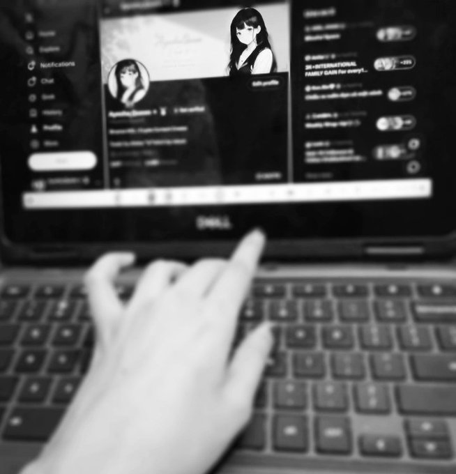 A black and white, slightly blurred photo shows a hand typing on a laptop keyboard, with the screen displaying a social media profile.