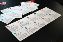 A set of informational or game cards spread out on a black table, with some arranged in rows and others stacked.