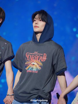 In this image, there are three people standing next to each other against a blue background that appears to be part of an art print or album cover. The main person in focus is wearing a gray t-shirt with red text that says "STARBOARD" on it and has a hoodie over his head. Another person is holding the arm of the main person, while the third person is partially visible behind them but not prominently featured in the scene. 

The image includes a caption, which reads: "260613 Let' s be together for a long, long time #씬롱 허씬롱 #alphadriveone". This seems to refer to an album cover or art print featuring the main person and their friends in various settings.
