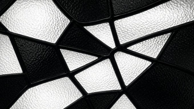 An abstract close-up image showing geometric patterns of textured white and black glass or plastic panels separated by dark frames.