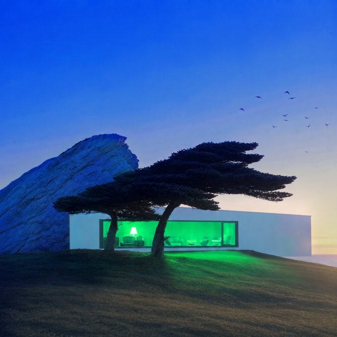 A modern white house with striking green-lit interior windows sits on a grassy hill at dusk, framed by a large tree and rocky outcrop with birds flying overhead.