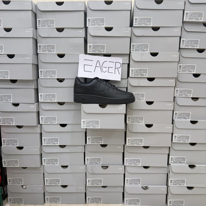 A black Nike sneaker sits atop a massive wall of stacked Nike shoe boxes, accompanied by a handwritten sign reading "EAGER." The playful "EAGER" message pairs with the "gm to those who gm back" post to express enthusiasm for greeting fellow crypto and sneaker enthusiasts.