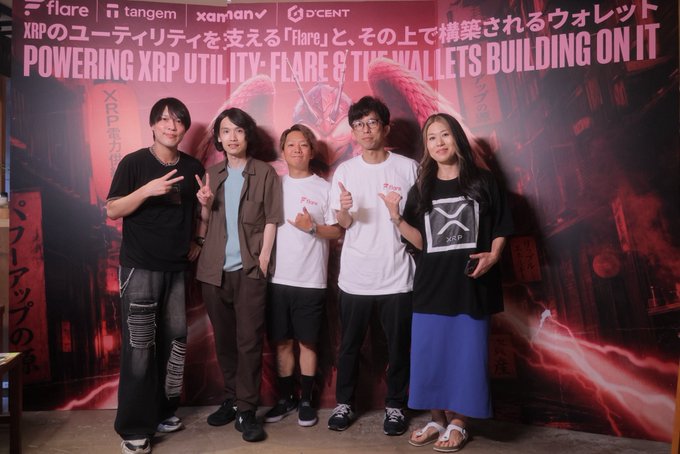 Five people pose together at an XRP-themed event, with a backdrop reading "POWERING XRP UTILITY - FLARE & THE WALLETS BUILDING ON IT" alongside sponsor logos for Flare, Tangem, Xaman, and DCENT, capturing an off-chain networking moment among the XRP/Flare community to complement the on-chain focus highlighted in the post.