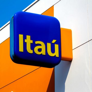 An Itaú bank sign, featuring blue and yellow colors, is mounted on an orange and white building facade.