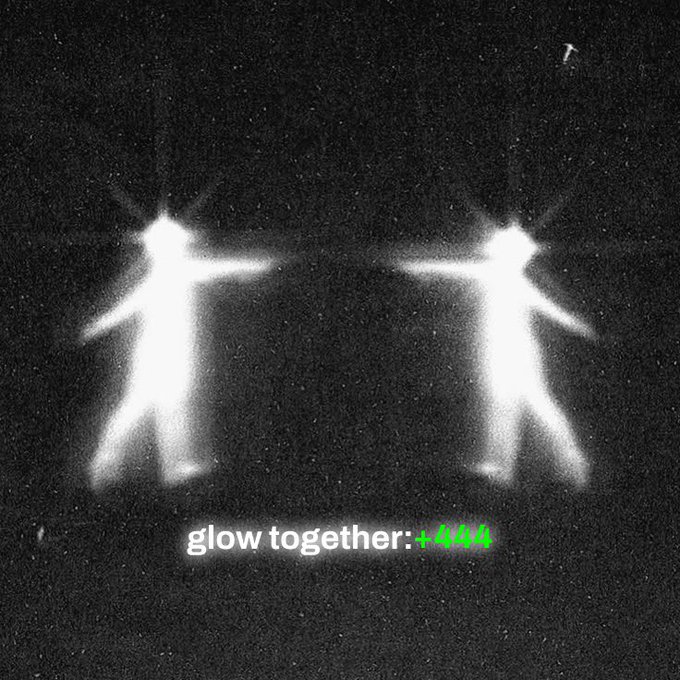 An artistic black and white photo showing two glowing figures standing with arms outstretched, with the text 'glow together:+4NN' displayed below in white and green.