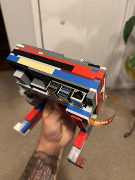 A person holds a colorful LEGO model of a computer displaying multiple cryptocurrency address QR codes, fitting the caption's theme of generating $KAS (Kaspa) addresses offline with a stylish, creative twist.