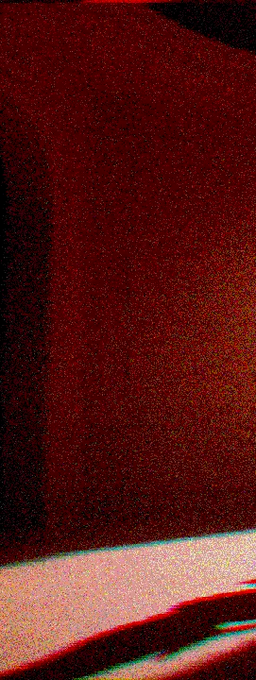 An abstract, dark red image with heavy grain or noise, showing indistinct curved shapes at the bottom and a sliver of light-colored area.