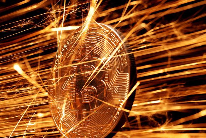 A golden Bitcoin ($BTC) coin is surrounded by dynamic, fiery spark-like streaks of light against a dark background, symbolizing intense market activity and momentum. The image visually captures the energy and volatility surrounding Bitcoin's price movement near the $65,000 support zone, with anticipation of a potential breakout toward $70,000 following a CPI signal.