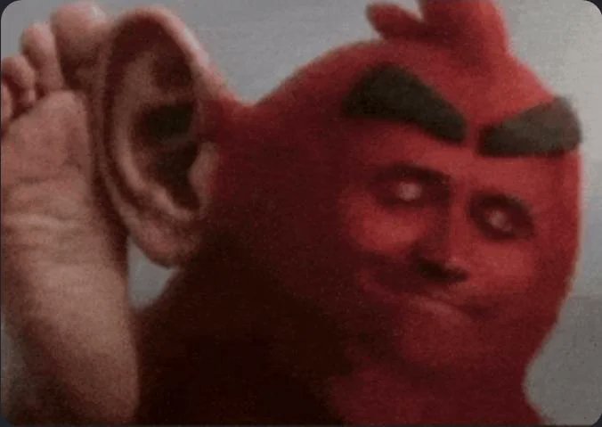 A humorous edited image showing a giant red Angry Birds character wearing a realistic human face, set against a cloudy sky background.