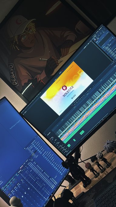 An overhead view of a music production workspace featuring a monitor displaying a DAW (digital audio workstation) with a Solstice sample pack by UVI loaded, alongside a screen showing an anime-style illustration of a character labeled 'DEBAYO'.