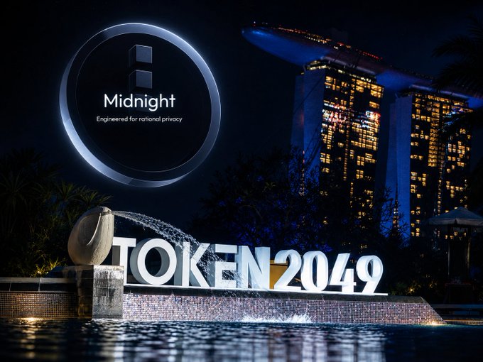 A nighttime promotional image featuring the "Midnight - Engineered for national privacy" logo overlaid on a scene with the "TOKEN2049" sign at Marina Bay Sands in Singapore.
