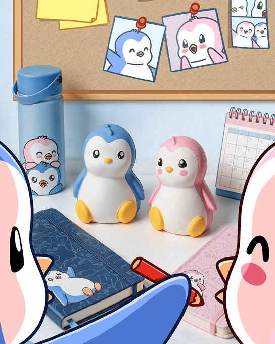 A colorful illustration of cute penguin figurines (one blue, one pink) on a desk surrounded by stationery, notebooks, a thermos, and a corkboard with penguin artwork pinned to it.