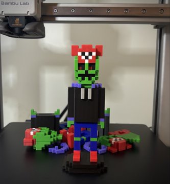 A 3D-printed pixel art figure of a zombie-like character in a black hoodie with red and green details, displayed on a Bambu Lab printer build plate.