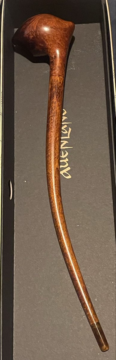 A wooden tobacco pipe rests inside a dark presentation box with the brand name "dunhill" printed on the interior lining.