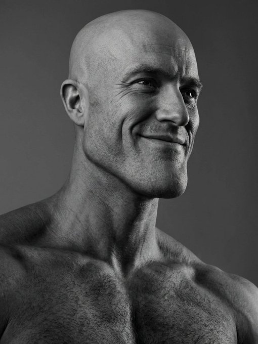A black-and-white photograph features a bald, shirtless man with stubble, smiling slightly as he looks off to the side, radiating a calm and confident demeanor. The image pairs with the post's vision board, visually embodying the optimistic anticipation and bullish confidence the author feels as they await the upcoming CLARITY vote and the prophesied "Uptober" crypto rally.