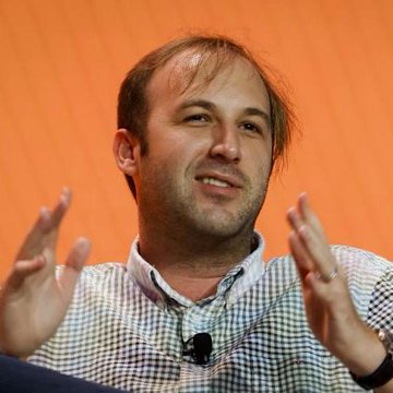The image features a man with short hair, wearing a plaid shirt, and his hands are clapping together. The background appears to be an orange wall, and there's also some text visible in the image that mentions "Bitcoin treasure trove Nakamoto sold" and the term "David Bailey's Nakamoto," both relating to Bitcoin transactions taking place.