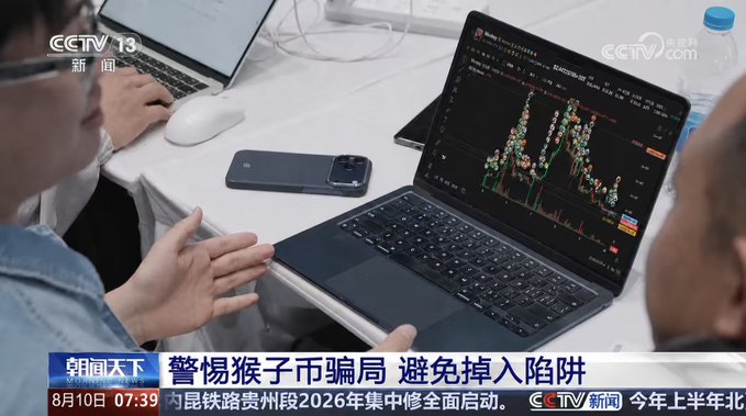A person in a denim jacket sits before a laptop displaying a candlestick cryptocurrency trading chart, with a smartphone resting nearby, as two other individuals look on. The CCTV-13 news broadcast features the headline "警惕猴子币骗局 避免掉入陷阱" (Beware of Monkey Coin scams, avoid falling into the trap), visually confirming the post's claim that the $MONKEY cryptocurrency was featured on Chinese state television as a scam warning.