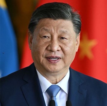 This is a headshot of Xi Jinping, the leader of China, standing in front of Chinese flags. The image likely accompanies the post's message to suggest that China's economy or currency is strong, making the US dollar "useless."