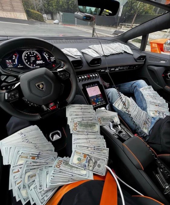 The interior of a Lamborghini Huracán (visible by the steering wheel badge and "P" gear indicator) is filled with stacks of $100 bills spread across the seats, dashboard, and center console. The image visually answers the post's question by showcasing how $10,000 in cash might look in a luxury supercar—portraying a fantasy of wealth changing one's life.