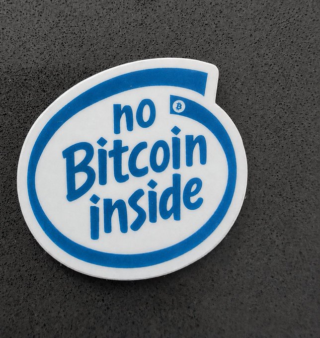 A die-cut sticker with a blue and white design features the text "no Bitcoin inside" along with a small Bitcoin logo, displayed against a dark gray surface.
