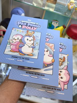 A hand holds a stack of three children's books titled 'The Adventures of Penguin & Polly' by Vixie Yuniar, with visible volumes including 'Journey to the Reef', 'Betrayal on the Reef', and 'A Wet Dawn on the Reef'.