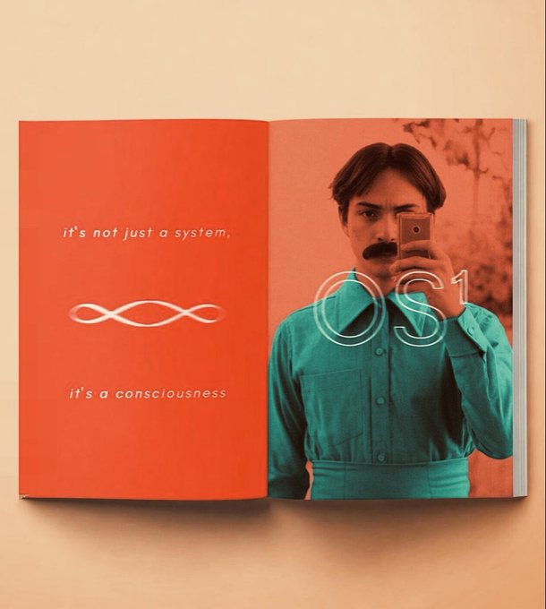 This image shows a book with the text "it's not just a system, it's a consciousness" and the text "OS1" next to a man taking a selfie. This relates to the post "Ansem Mode : Coming Soon…" by presenting the concept of "OS1" as a conscious system.