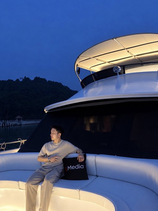 A man relaxes on the plush seating of a luxury yacht at dusk, with a black pillow displaying "Media" beside him, juxtaposing a moment of leisure against the implied success of a "generational run."