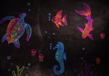 A black paper scratch art drawing revealing neon-colored sea creatures including a sea turtle, goldfish, seahorse, jellyfish, and coral designs in vibrant pink, blue, green, and yellow hues.
