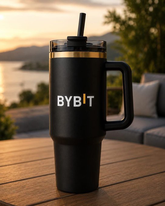 A matte black tumbler with "BYBIT" branding sits on a wooden table, ready for a refreshing drink as part of a relaxed "GM Legends" greeting to the crypto community. The scenic sunset backdrop complements the casual, optimistic vibe of the morning shout-out.