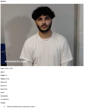 A mugshot of a young man with dark curly hair wearing a white t-shirt, displayed on a US Marshals page with details including name 'CHET, KYLE', Age 23, Height 5'7", Weight 170 lbs, and charges for 'FEDERAL OFFENSE/Federal misdemeanor offense'.