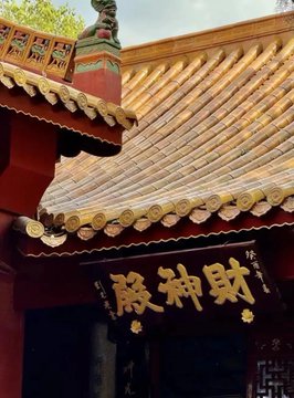The image features a large building with an ornate roof, possibly a temple or another type of historic structure. The roof has gold accents that give it an elegant appearance. A sign can be seen hanging from the top of the building, which is written in Chinese characters. The overall scene suggests that this building might hold cultural or historical significance and could potentially be located in China.