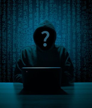 The image shows a person wearing a hooded sweatshirt sitting at a desk holding a laptop computer. The question mark above their head suggests that they might be a hacker, possibly targeting a Bitcoin wallet or cryptocurrency exchange system. The person appears to be draining Ether from an Ethereum MEV bot, which has been targeted and drained of around $7.5M in per-Block currency. They are also using the money laundered through this cryptocurrency attack on various crypto platforms.