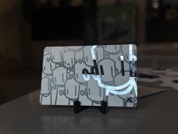 A gray card or print featuring repeated line drawings of padlocks, displayed upright on a small black stand.