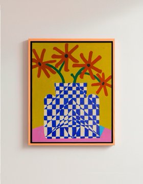 A framed art print on a beige wall depicting red daisies in a blue-and-white checkered vase against a yellow background.