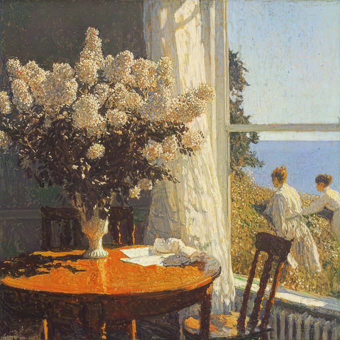 An impressionist painting shows a bright interior with a vase of white flowers on a sunlit table, while through an open window two women in white dresses enjoy a view of the sea.