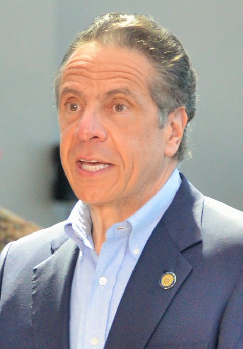The image shows former New York Governor Andrew Cuomo speaking at an event, captioned as him urging Congress and the White House to pass the CLARITY Act to establish crypto regulatory rules and accelerate innovation.