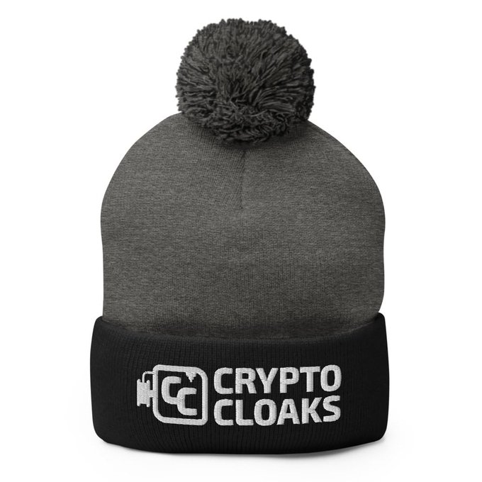 A gray and black knit beanie hat with a pom-pom on top, featuring the embroidered white text and logo 'CRYPTO CLOAKS' on the black cuff.