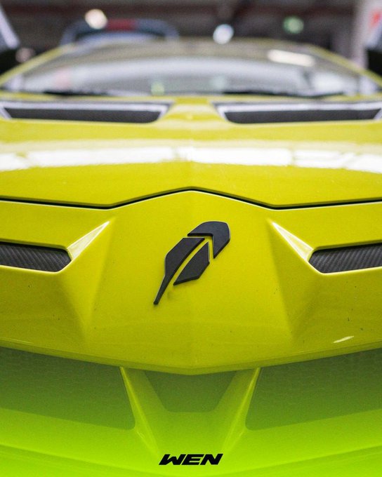 A close-up shot of a bright yellow-green Lamborghini's front hood featuring the iconic black bull emblem, paired with "WEN" text at the bottom, visually playing on the "Wen Lambo" meme referenced in the post about the WEN token's listing on Robinhood.