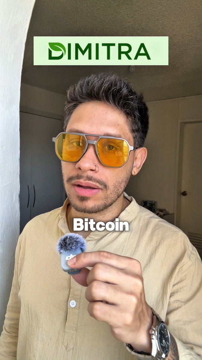 A man wearing yellow-tinted sunglasses and a beige shirt with a 'DIMITRA' logo overlay and 'Bitcoin' caption, holding a small DJI microphone.