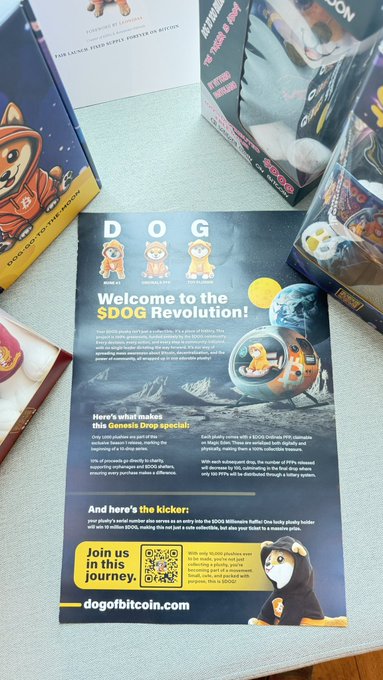 A promotional flyer titled "Welcome to the $DOG Revolution!" for DOG (Dog on Bitcoin), surrounded by merchandise including a plushy and boxes, with text mentioning a "Genesis Drop" and "Join us in this journey" via QR code.