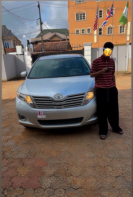 A man stands proudly next to his silver Toyota Venza in a driveway, with a "L" (learner) sign on the front bumper. The image celebrates his achievement of getting a new driver's license key, matching the caption "GOD DID. I DID NEW KEY."

Visible text/signs: "Toyota" logo on the grille, and an "L" (Learner) sign on the front bumper.