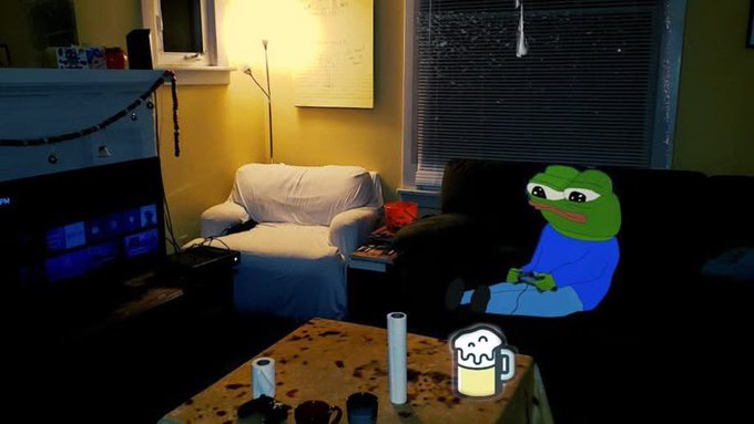 A dimly lit living room scene featuring an inflatable Pepe the Frog doll wearing a blue shirt sitting on a dark couch, with a blank white chair, a floor lamp, and drawn-on white candles and a beer mug on the coffee table.