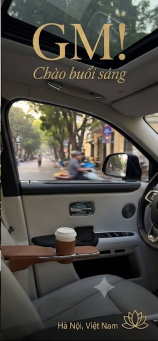 View from inside a car in Hà Nội, Việt Nam with 'GM! Chào buổi sáng' text overlay, showing a coffee cup and a street scene with a person on a scooter.