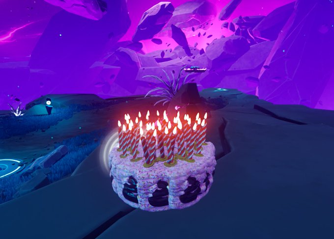 A birthday cake adorned with lit, colorful striped candles sits on a ledge in a surreal, vibrant purple-pink alien landscape, celebrating another successful event as mentioned in the post's "Proof of Cake" message tagging ClassicsCrypto and other community members.